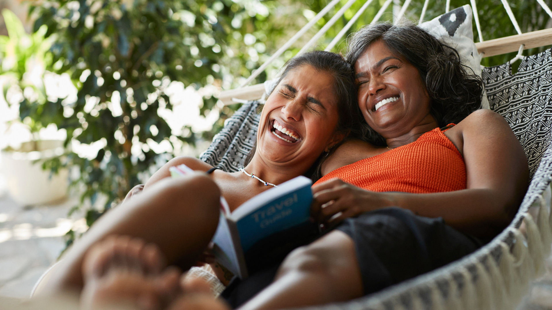 Cheerful woman lying with mother in hammock