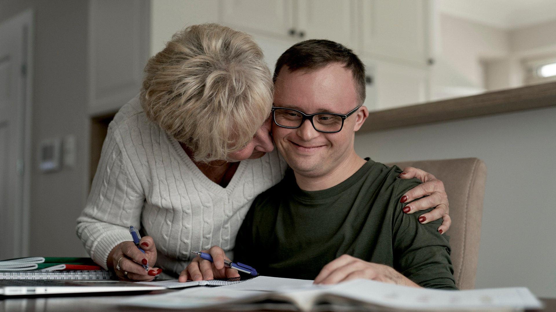 Mother hugging son with disability while learning at home - Support Coordination