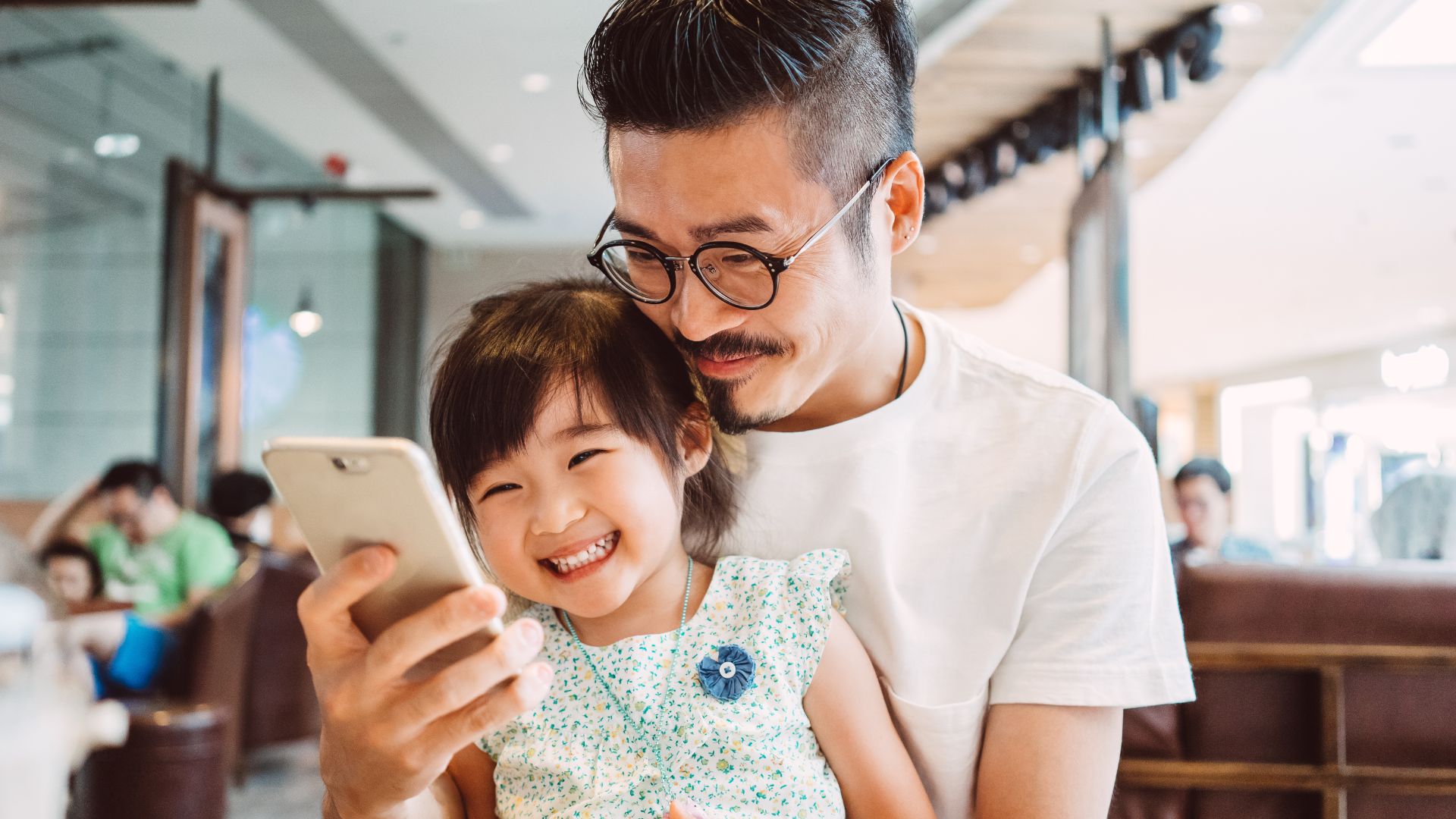 Young dad using smartphone with little daughter