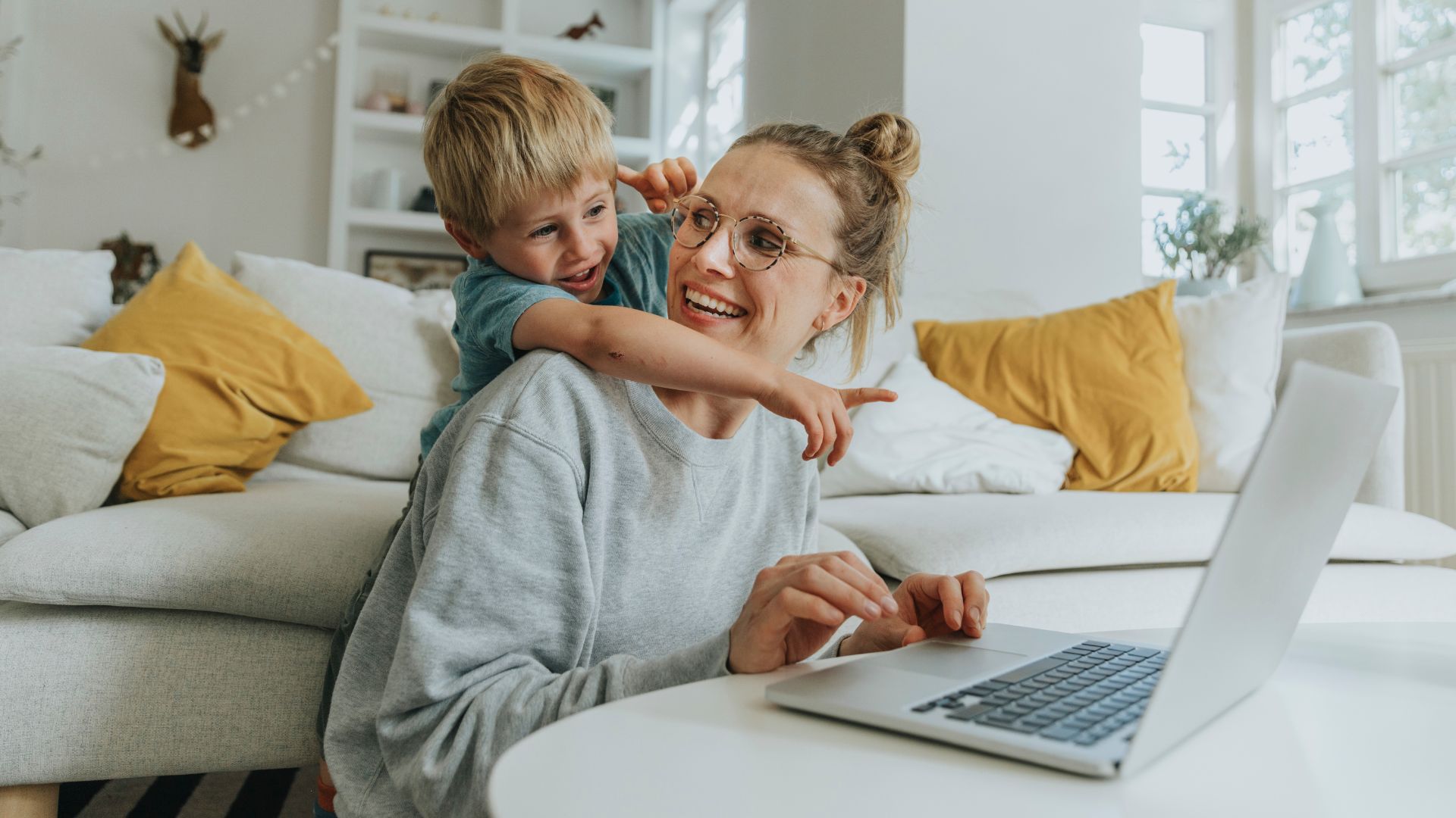 Boy pointing at laptop showing the myintegra portal while standing behind mother at home