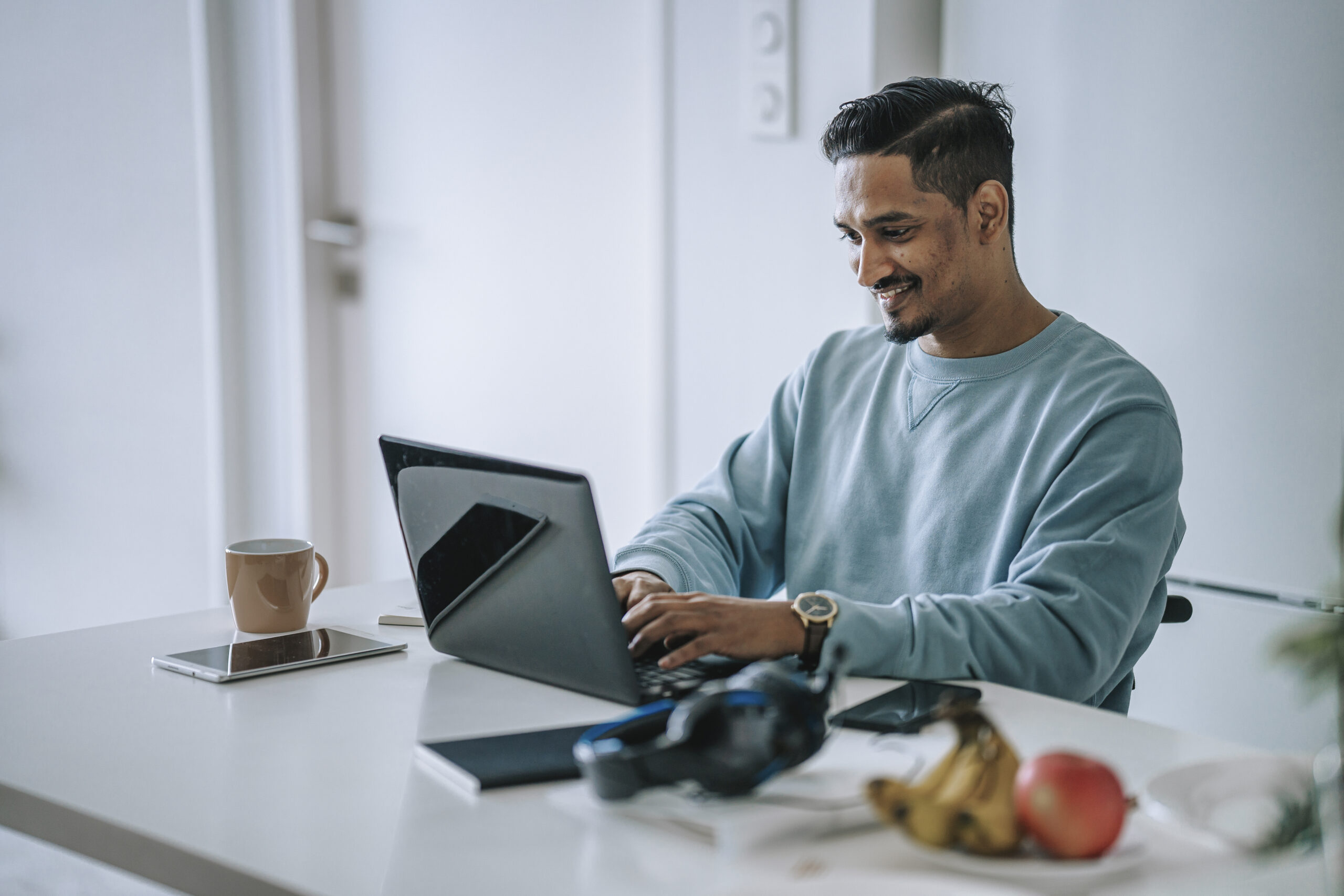 Asian Indian man with disability working at home typing using laptop smiling