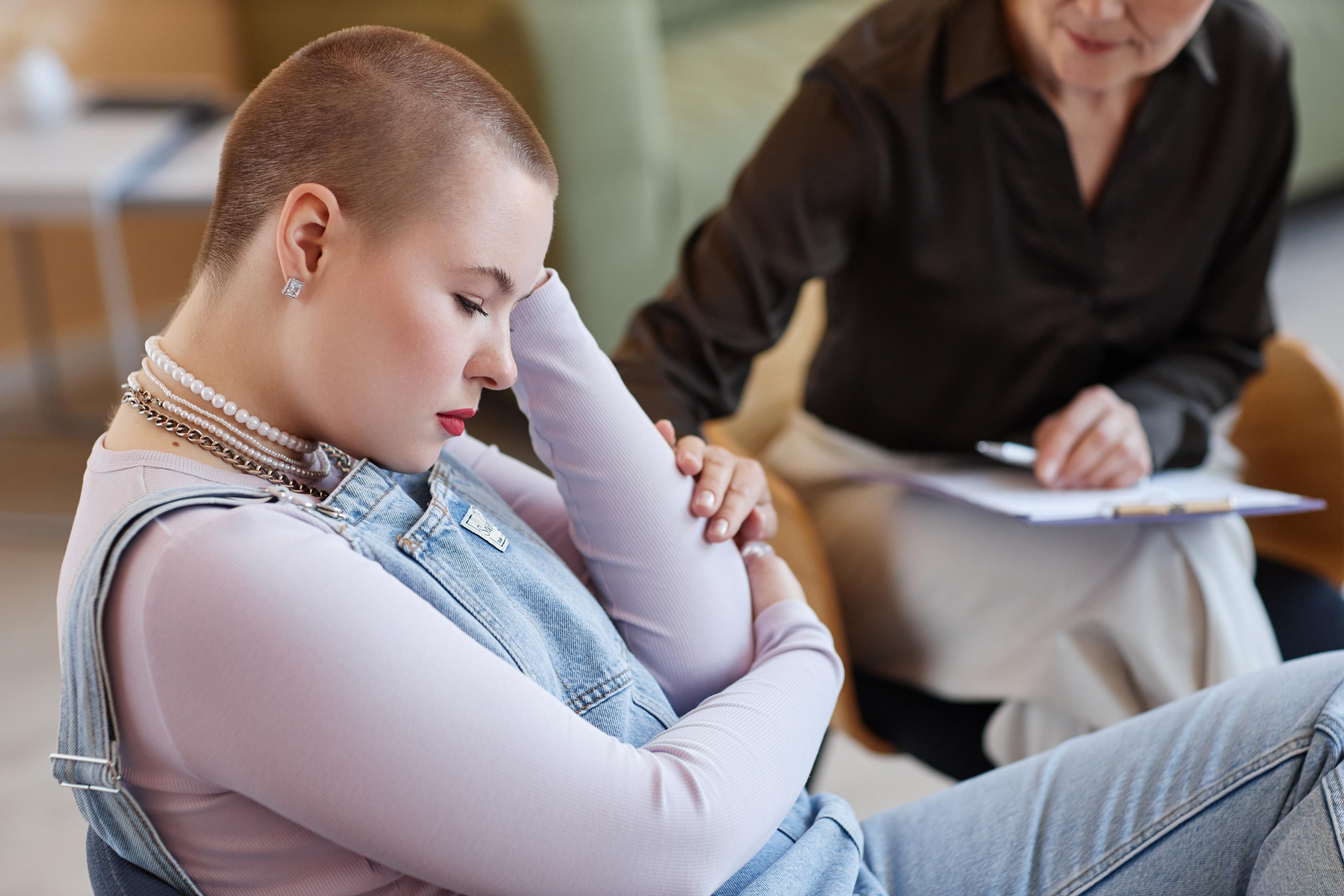 A stressed young adult sitting while a therapist takes notes, illustrating the exhaustion of executive function challenges.