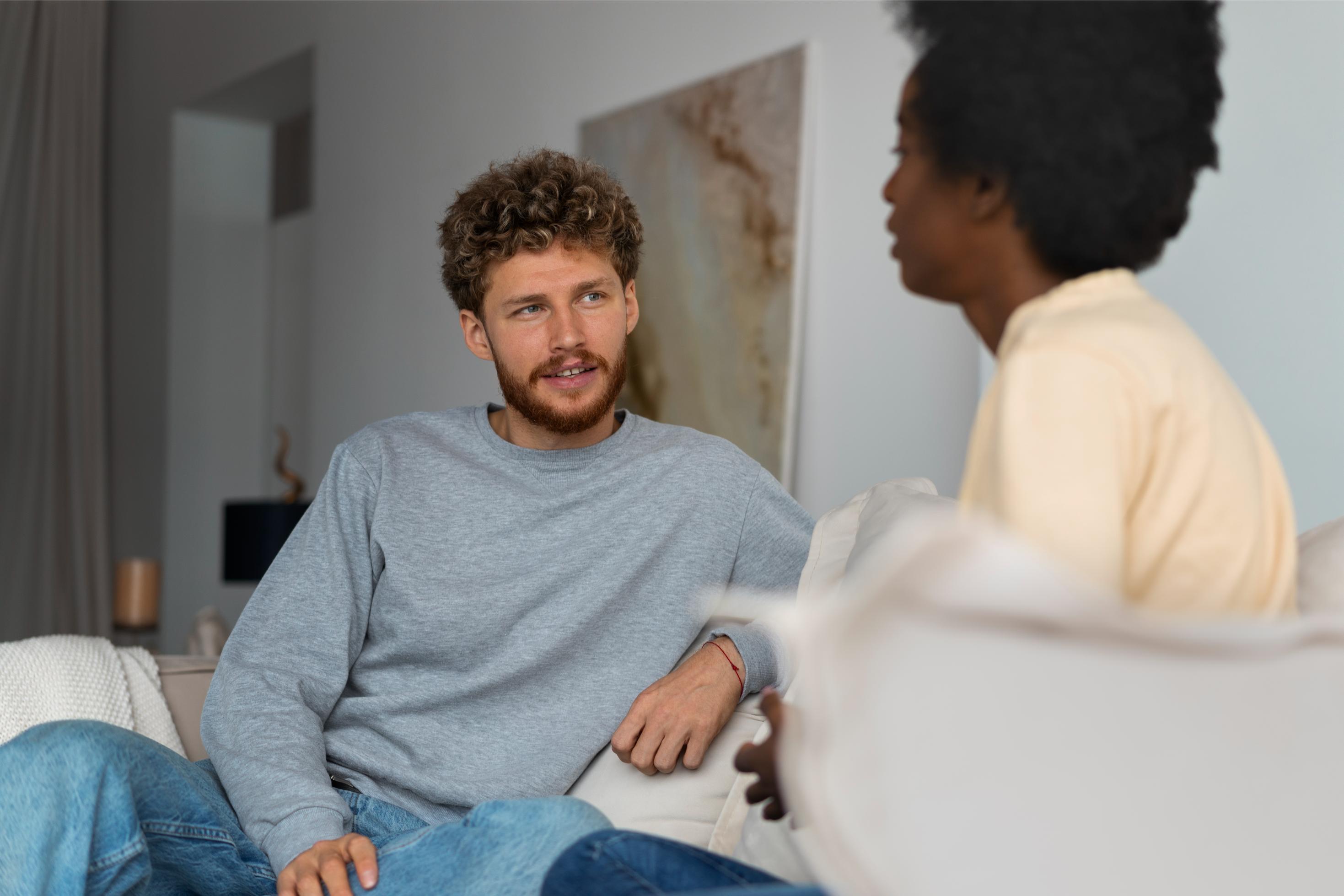 Two young adults conversing on a couch, representing therapy or support work for ADHD and co-occurring conditions.
