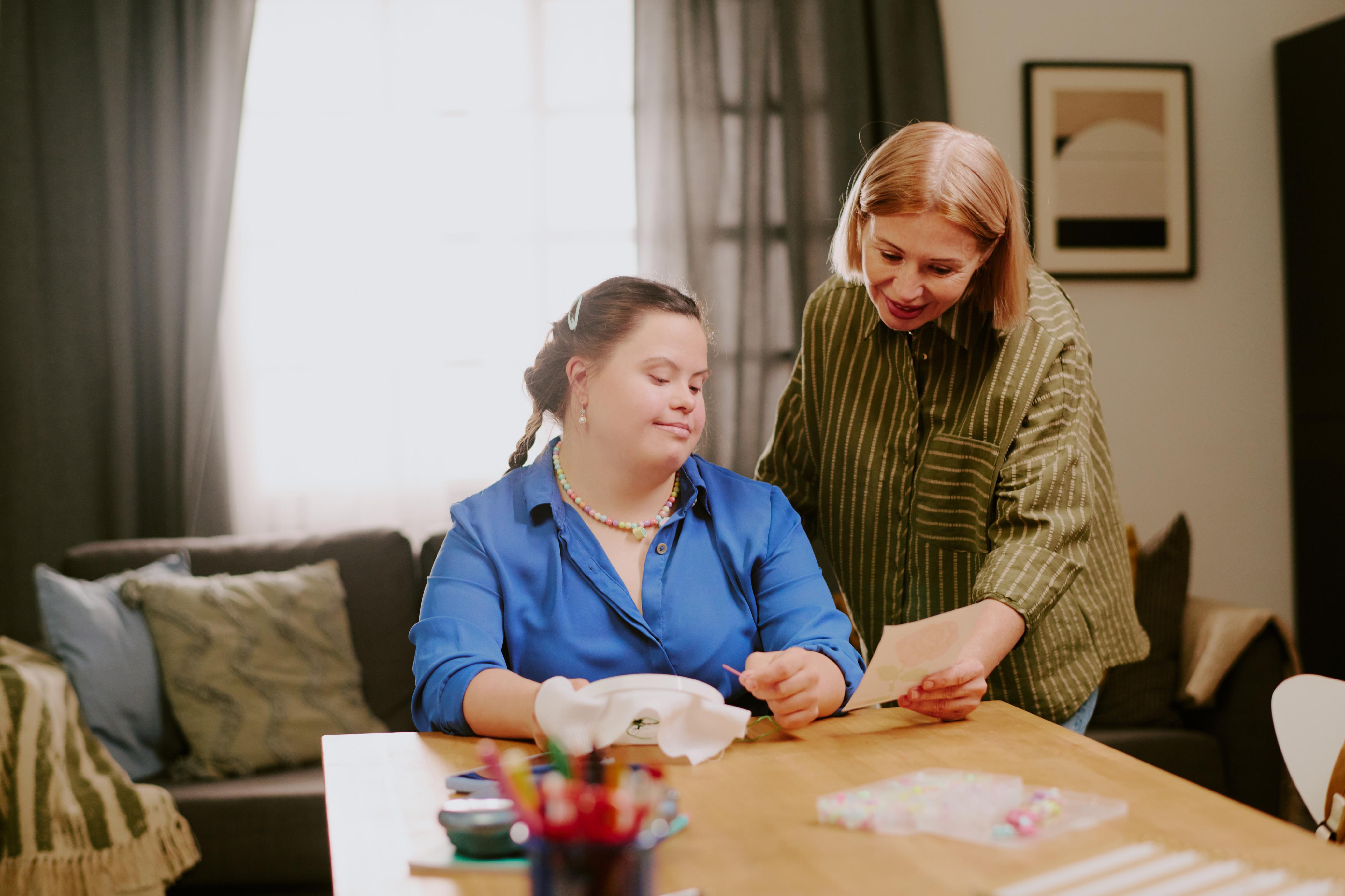 A support worker assisting a participant at a table, showing how plan management lets you focus on your supports.