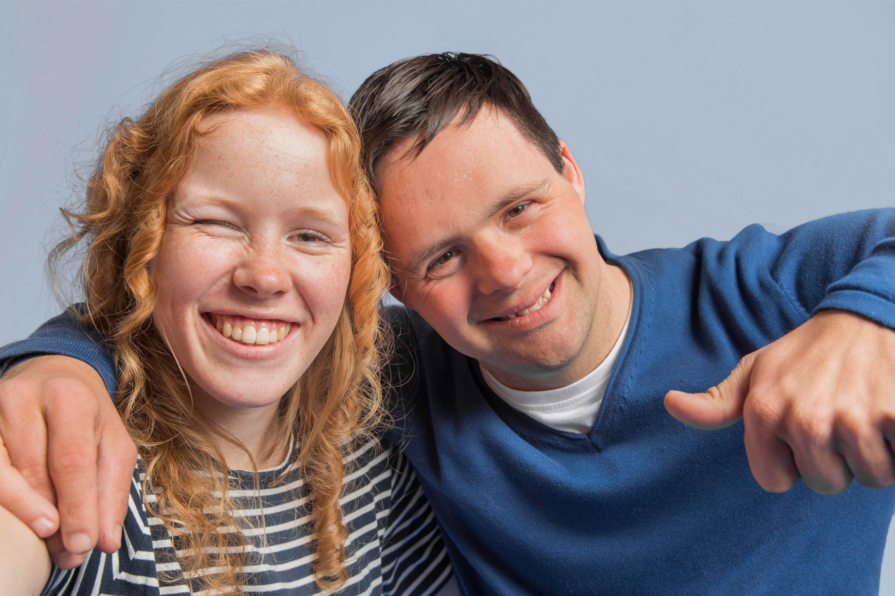 Two smiling young adults embracing, representing NDIS participants empowered to manage their funding choices.