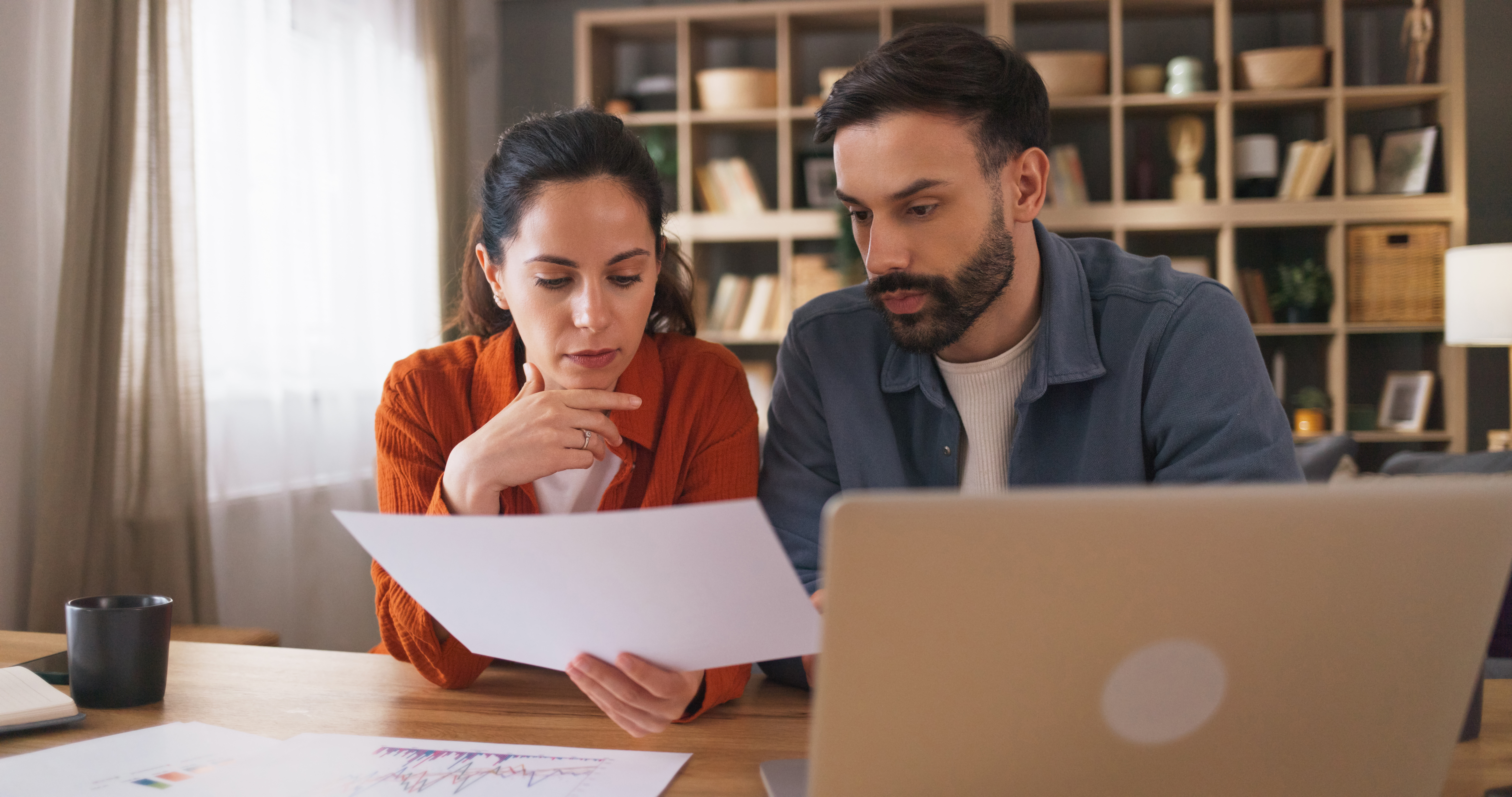 Man and a woman working together with a laptop and papers, concentrating.