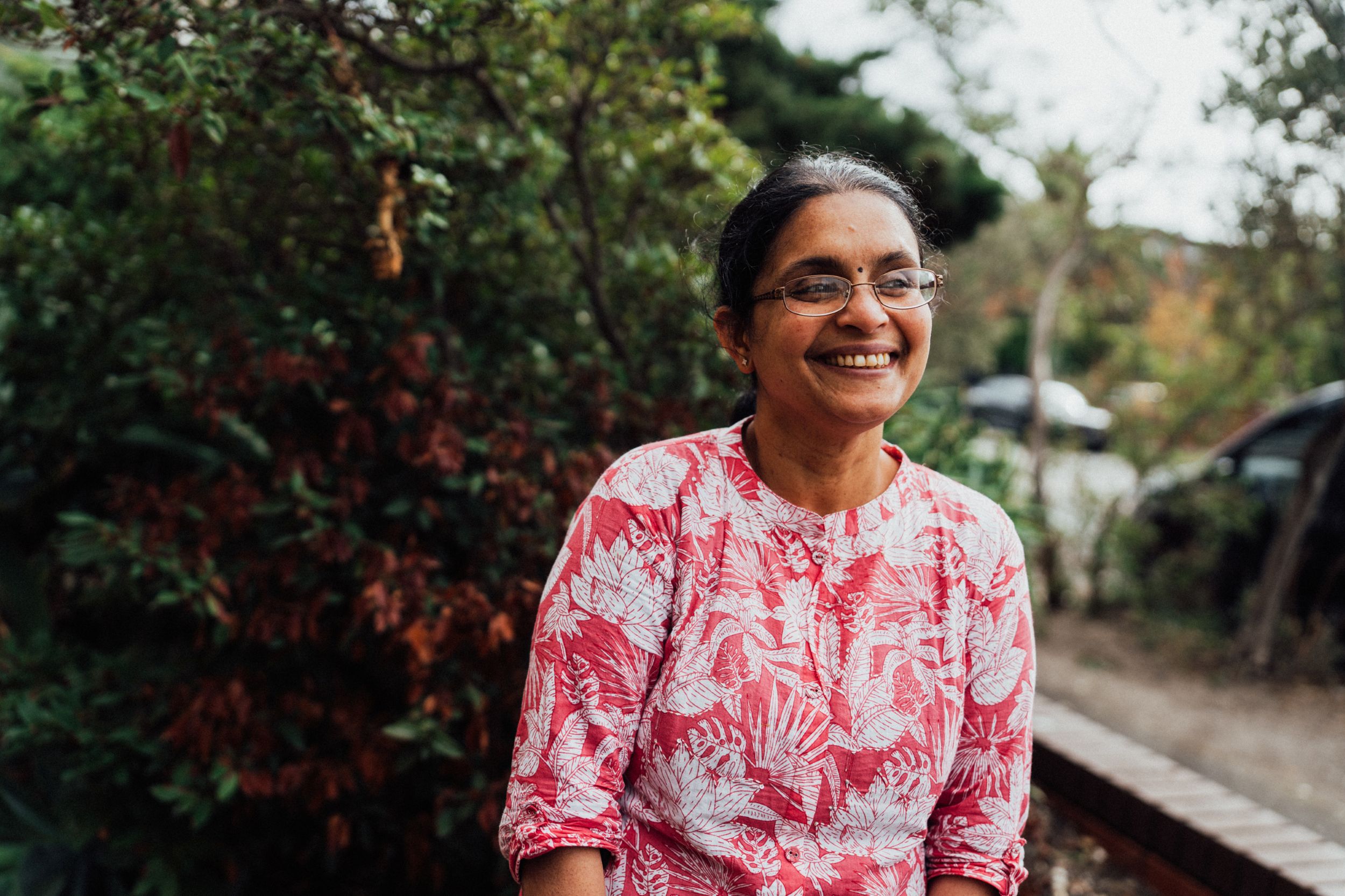 Woman smiling happily, looking content in a garden.
